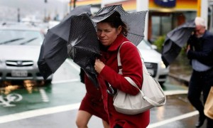 An urban dweller struggles against strong, gusty winds. Credit: The Guardian.